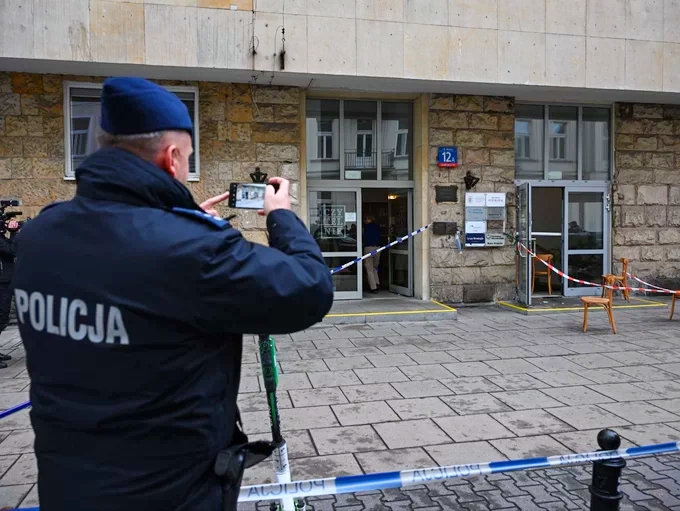 Atak na biuro PO. Policjant fiksuje miejsce zdarzenia.