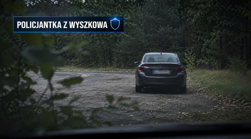 Anonimowy samochód sfotografowany od tyłu na leśnej drodze, z rozmytą tablicą rejestracyjną – ilustracja redakcyjna.